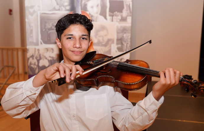 Latino Arts Strings Program student Hector Hernandez with a klezmer violin from Violins of Hope. Photo courtesy of Latino Arts